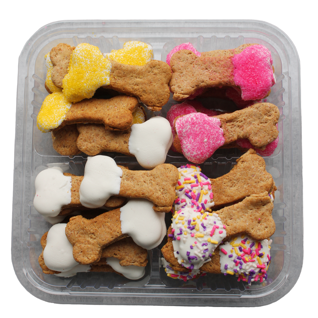 Assorted dog treats in the shape of bones with different toppings in a clear container.